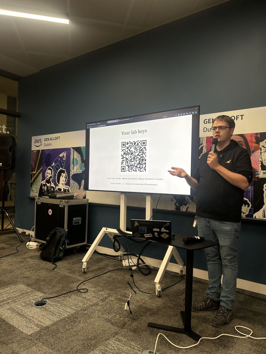 A speaker at the AWS Gen AI Loft in Dublin presenting a slide titled Your lab keys, with a QR code on screen